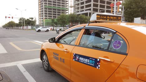Xian,-China---August-2019-:-Orange-taxis-waiting-on-a-crossroad-for-a-green-traffic-light-sign,-centre-of-Xian-in-summer,-Shaanxi-Province