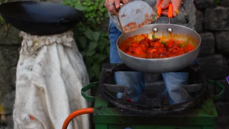 A-slow-motion-shot-of-a-street-vendor-increasing-the-fire-in-the-stove-and-frying-Chilly-Chicken-in-a-Pan-to-sell-in-the-streets-of-Darjeeling