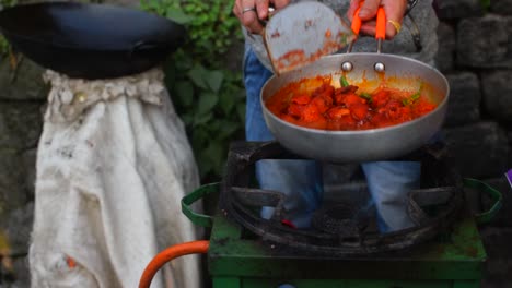 Eine-Zeitlupenaufnahme-Eines-Straßenverkäufers,-Der-Das-Feuer-Im-Ofen-Anheizt-Und-Kühles-Hühnchen-In-Einer-Pfanne-Brät,-Um-Es-In-Den-Straßen-Von-Darjeeling-Zu-Verkaufen