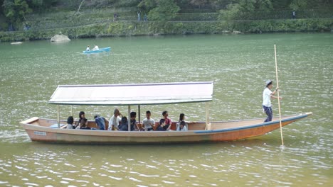 Mann-Steuert-Ein-Boot-Im-Traditionellen-Asiatischen-Stil-Durch-Die-Flüsse-In-Kyoto,-Japan,-Sanfte-Beleuchtung-4k