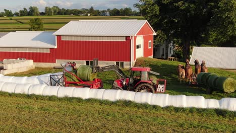 Amish-Traktor-Mit-Stahlrädern-Legt-Runde-Heuballen-Auf-Die-Wickelmaschine,-Antenne