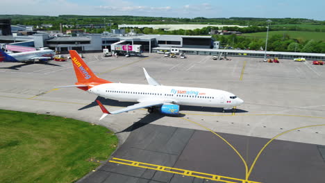 Tracking-panning-right-shot-of-a-Sunwing-airplane-taxiing-to-its-arrival-terminal-gate