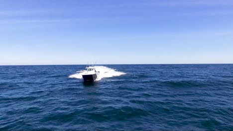 Front-view-of-boat-riding-in-the-open-ocean-on-a-bright,-sunny-day-with-blue-water