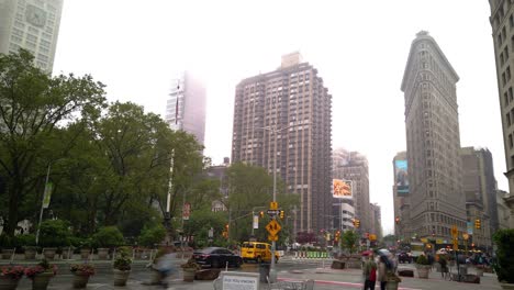 Motion-Time-Lapse-of-the-traffic-at-Madison-Square-Park-and-the-Flatiron-Building-on-a-rainy,-cloudy-summer-day-at-the-intersection-of-5th-Avenue-and-Broadway,-Manhattan,-New-York-City,-USA
