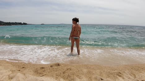 Chica-Sola-En-La-Orilla-De-La-Playa-Entrando-Lentamente-En-El-Agua
