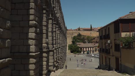 POV-Ansicht,-Die-Stufen-Neben-Dem-Wasserlauf-Des-Antiken-Aquädukts-In-Segovia,-Spanien,-In-Der-Nähe-Von-Madrid-In-Zeitlupe-Hinuntergeht