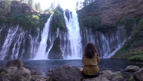 4K-footage-of-Burney-Falls-with-a-woman-enjoying-the-cool-mist-on-a-hot-summer-day