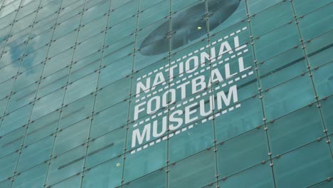 Schild-Des-National-Football-Museum-An-Der-Seite-Des-Gebäudes,-Touristenattraktion,-öffentlicher-Standort,-Großraum-Manchester-City,-Sommer,-Sonniger-Tag,-Touristenattraktion,-Wahrzeichen-4k-25p