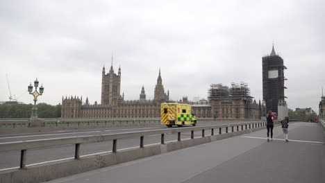 Una-Ambulancia-Pasa-Por-Las-Casas-Del-Parlamento-Mientras-Cruza-Un-Puente-De-Westminster-Casi-Desierto-Durante-El-Brote-De-Coronavirus