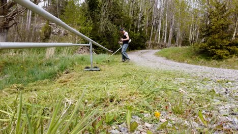 Timelapse-of-young-man-cutting-long-grass-with-a-petrol-strimmer
