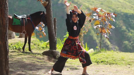 a-young-woman-practicing-martial-arts-on-a-hill-with-a-horse-background