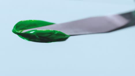Mit-Einem-Spachtel-Wird-Grüne-Farbe-Auf-Eine-Weiße-Papierleinwand-Aufgetragen