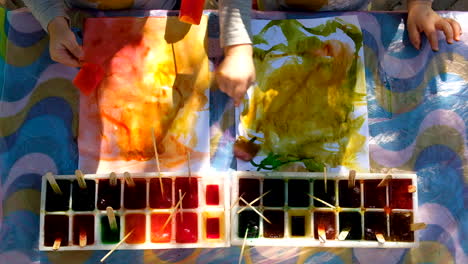 Twins-doing-ice-painting,-art-activity,-top-down-shot