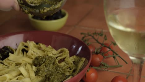 Serving-green-pesto-onto-tagliatelle-pasta-close-up-shot