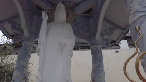 Stabilisierte-Schwenk-Detailaufnahme-Von-Drachenköpfen,-Die-Sich-Zu-Einer-Wunderschönen-Weißen-Buddha-Statue-Und-Weiter-Zu-Einem-Anderen-Drachenkopf-Bewegen