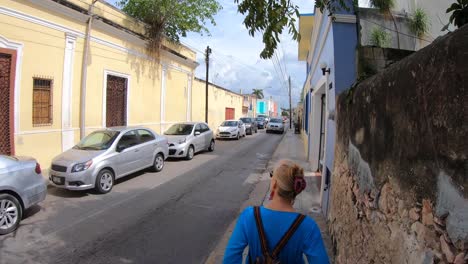 Hiperlapso-De-Caminar-Por-Las-Calles-Del-Barrio-Con-Una-Mujer-Rubia-Frente-A-La-Cámara-De-Merida,-Yucatan,-Mexico