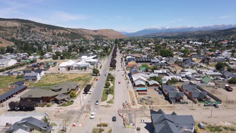 Dolly-in-flying-above-Esquel-city-main-street-surrounded-by-Andean-mountains,-Patagonia-Argentina