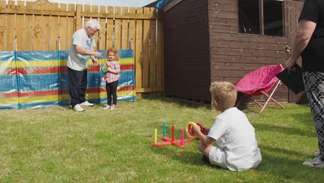 Großeltern-Vergnügen-Sich-Im-Sommer-Beim-Spielen-Mit-Enkelkindern-Im-Hintergarten