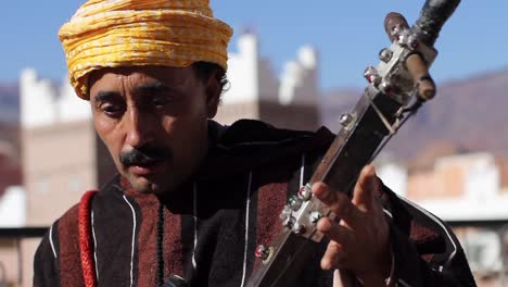 Closeup-of-Berber-musician-looking-at-camera-while-playing-rabab-and-singing-in-Taffraoute,-Morocco