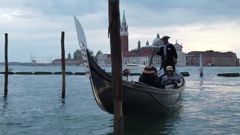 Tourists-on-Venice-gondola,-gondolier-steering-boat-from-canal-dock,-slow-motion