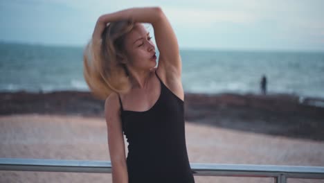 Portrait-of-a-blonde-caucasian-woman-on-a-beach-touching-her-hair-on-windy-day