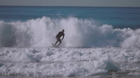 Ein-Erfahrener-Surfer-Steigt-Von-Seinem-Surfbrett-Ab,-Während-Die-Welle-Auf-Den-Strand-Trifft-–-Isolierte-Zeitlupe
