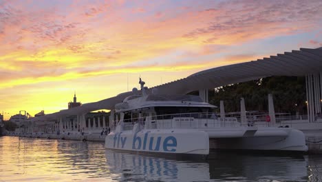 Colorful-Sunset-Over-Promenade-in-Malaga,-White-Yacht-in-Foreground