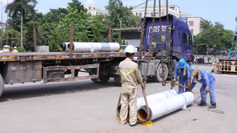 Workers-Securing-Lifting-Belts-On-Two-Heavy-Circular-Columns-For-Loading