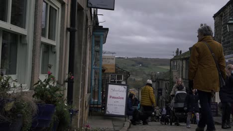 Shoppers-browsing-in-cobbled-street-in-Yorkshire-village-Haworth-medium-panning-shot