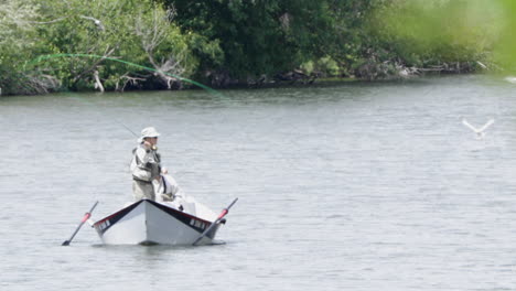 Woman-fly-casting-from-the-bow-of-a-small-boat-on-Snake-River,-Chester-Idaho