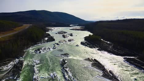 Liard-River-Mit-Stromschnellen-In-Kanada-An-Einem-Eisigen-Tag,-Verfolgungsdrohnenaufnahme