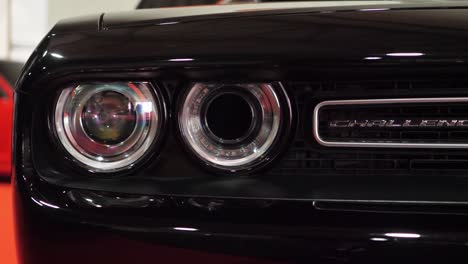 Schwarzer-Dodge-Challenger-Der-3.-Generation-Eines-Sportwagens,-Logo-Mit-Buchstaben-Auf-Der-Vorderseite-Und-Scheinwerfer