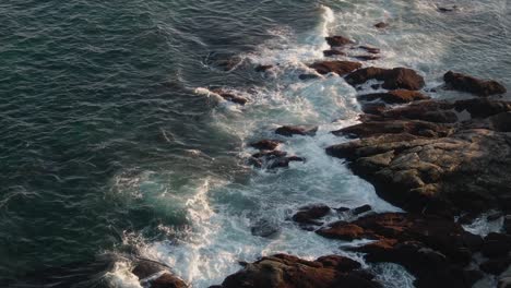 Perfect-waves-splashing-on-the-rocky-shores-of-Gloucester,-Massachusetts--aerial
