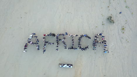 overhead-aerial-shot-of-people-forming-the-word-"Africa"-in-the-Namib-desert