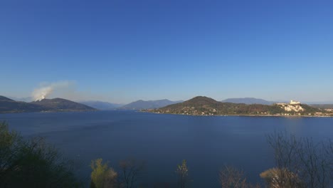 Panoramic-view-over-Maggiore-lake-and-smoke-from-mountain-due-to-burning-fire-close-to-Nebbiuno-in-Piedmont,-Italy