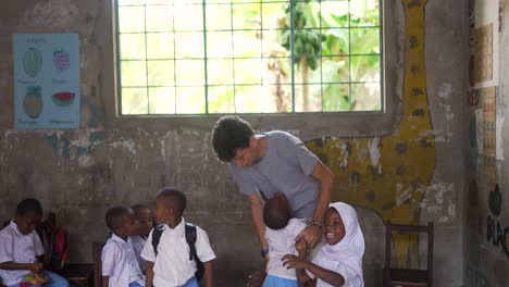 Niños-Africanos-Felices-Jugando-Y-Dando-Un-Abrazo-A-Un-Voluntario-De-Maestro-Caucásico-Blanco-En-La-Escuela-En-África-4k