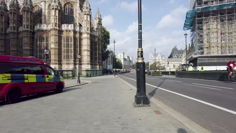 POV-Shot-walking-along-Abingdon-Street,-2-police-vehicles-parked-outside-The-Lady-Chapel-,-London,-England