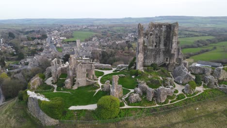 Legendary-Corfe-Castle-perched-on-hill-and-village-in-background,-County-Dorset-in-England