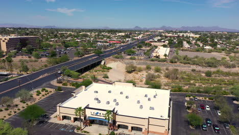 Drone-Flies-Over-Building-Of-Lazboy-Store-With-Vehicles-Driving-On-Asphalt-Road-In-Tucson,-Arizona,-USA