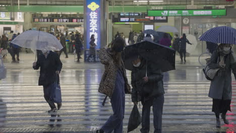 People-Rushing-To-Cross-The-Road-Outside-The-Shinjuku-JR-Station-During-Snowing-In-City-Of-Tokyo,-Japan