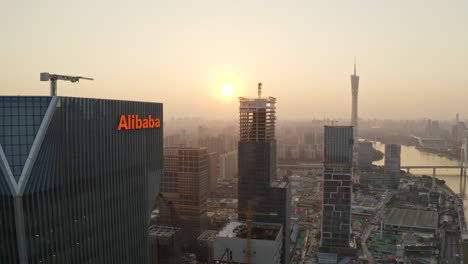 Vuelo-Cercano-Cerca-Del-Edificio-De-Oficinas-Del-Grupo-Alibaba-Con-Revelación-De-La-Torre-Del-Cantón-Y-El-área-Del-Centro-De-Cbd-En-Segundo-Plano-En-La-Hermosa-Puesta-De-Sol-Dorada