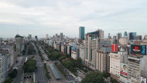 Aerial-dolly-in-of-Obelisk-in-9-de-Julio-avenue-surrounded-by-buildings-and-billboards-in-Buenos-Aires