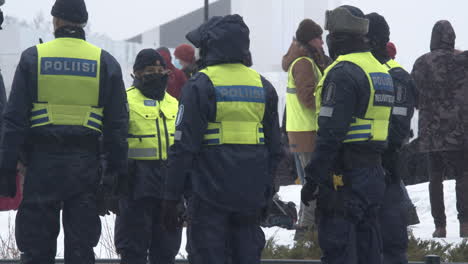 Plano-Medio-Ancho-Que-Muestra-A-Un-Grupo-De-Policías-Armados-De-Servicio-En-Helsinki-Durante-Una-Manifestación-Por-Las-Restricciones-De-Covid-19,-Día-Frío-Y-Nevado