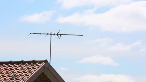 Partly-cloudy-sunny-afternoon-scene-over-typical-Australian-suburban-roof-line-and-TV-antenna