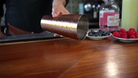 Latin-Bartender-rolling-copper-shaker-over-bar-and-picking-up-in-slow-motion