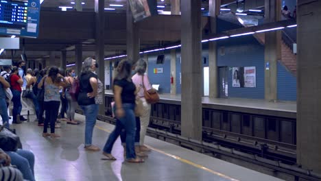 Los-Viajeros-Con-Máscaras-Faciales-Hacen-Fila-Para-Tomar-El-Próximo-Tren-Del-Metro