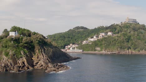 Rocky-cliffs-and-view-of-San-Sebastian-city,-low-angle-drone-view