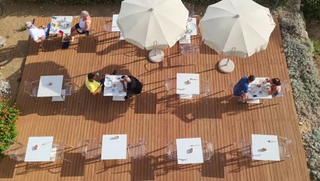 People-eat-and-drink-outdoor-breakfast-at-hotel-restaurant-enjoying-sunny-summer-day