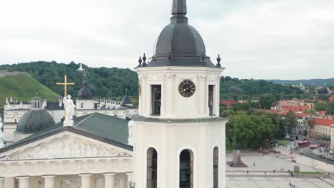 AERIAL:-Close-Up-of-Vilnius-Bell-Tower-with-Cathedral-in-Background-and-Forest-in-Landscape