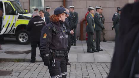 Mujer-Policía-Inspeccionando-A-Karl-Johan,-Oslo-Durante-El-Desfile-Militar-Con-Soldados-Detrás